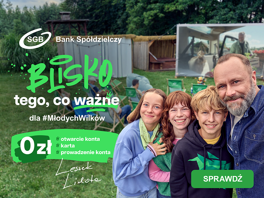 Leszek Lichota z uśmiechniętymi dziećmi patrzy prosto na obserwatora, w tle podwórko z kinem letnim.